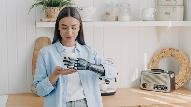 A person with a bionic arm holding a mug