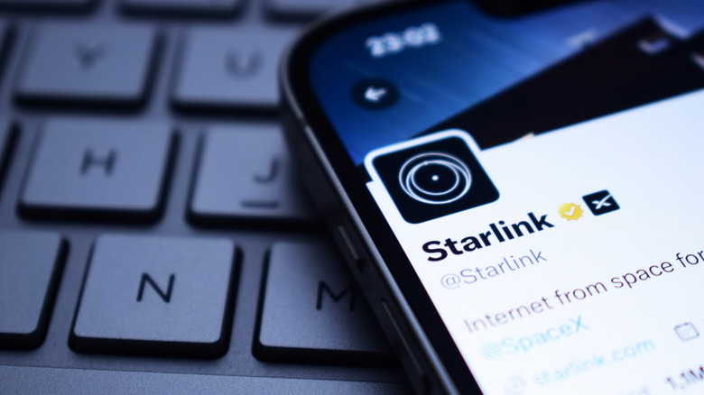 Close up of the Starlink logo on X on smartphone screen with keyboard underneath.