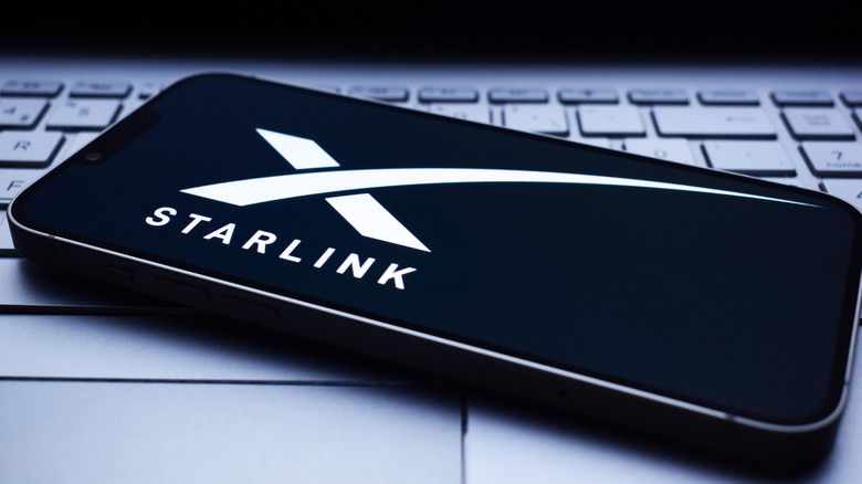 The Starlink logo on an iPhone resting on a laptop's keyboard.