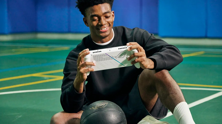 A man smiling while playing on a white ROG Ally gaming handheld