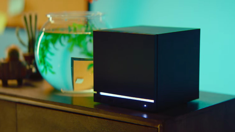 A Steam Machine sitting on a dark wood surface with a fishbowl next to it