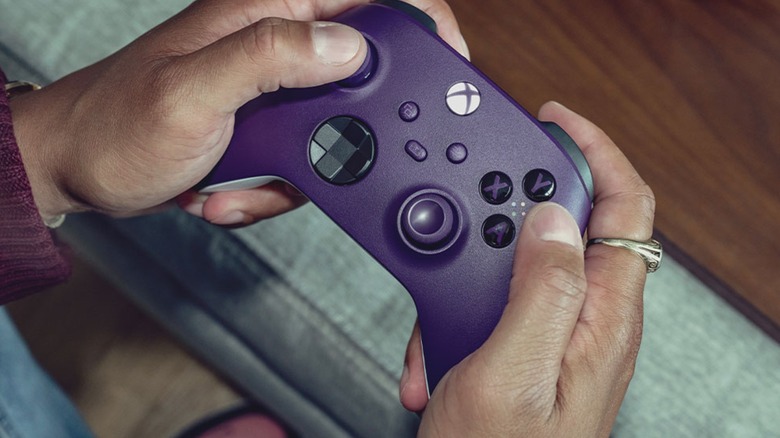 Person on couch playing game with purple Xbox Series controller