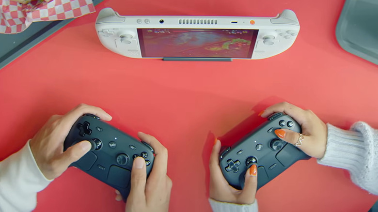 An overhead shot of two players holding the new Steam Controllers as they play a game on a Steam Deck, only their hands can be seen