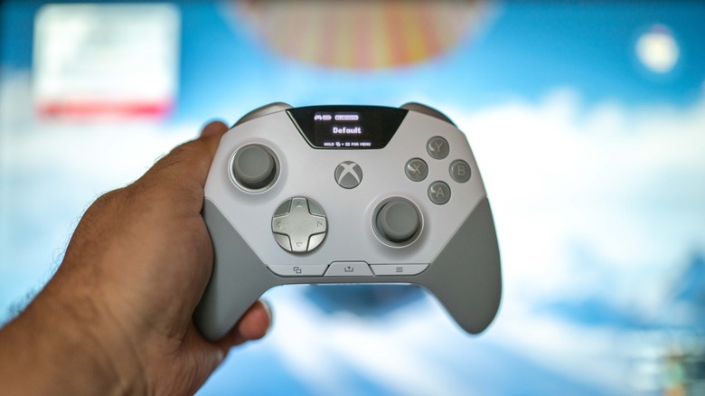The SteelSeries Aeon Pro controller held in a hand in front of a monitor.