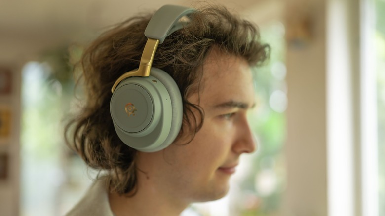 The SteelSeries Arctis Nova Elite worn by a young man in a bright, out of focus room.