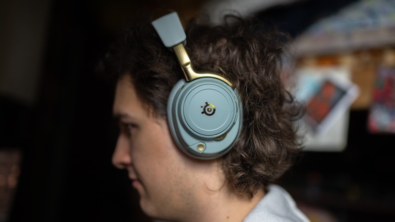 The SteelSeries Arctis Nova Elite worn by a young man in front of an out of focus room.