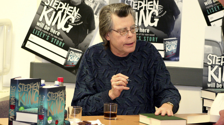 Stephen King autographing books of his at a table.