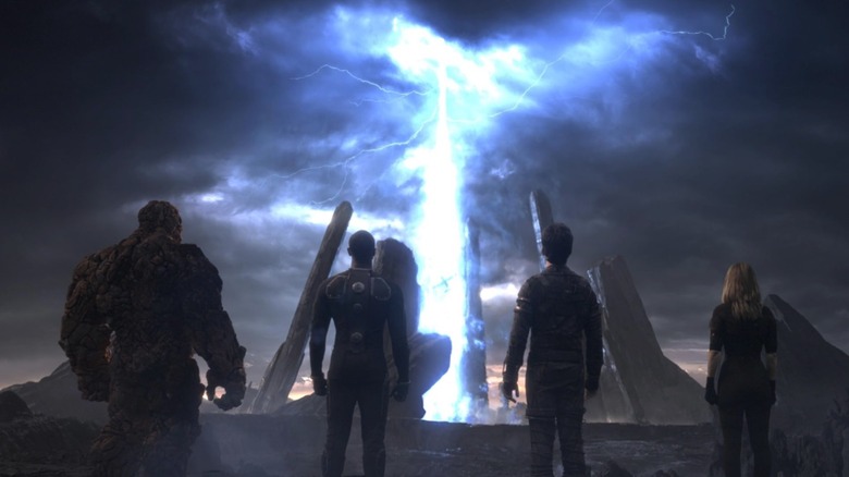 Jamie Bell as Ben Grimm, Michael B. Jordan as Johnny Storm, Miles Teller as Reed Richards, and Kate Mara as Sue Storm stood with their back to us looking at a portal in Fantastic Four 2015