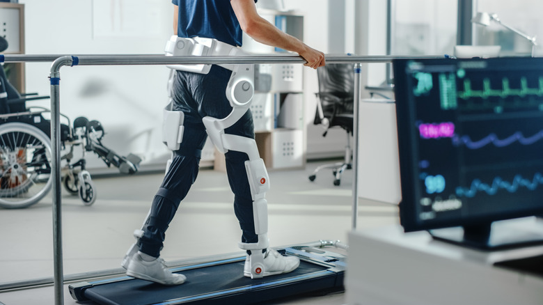 A person wearing an exoskeleton on their legs walking on a treadmill