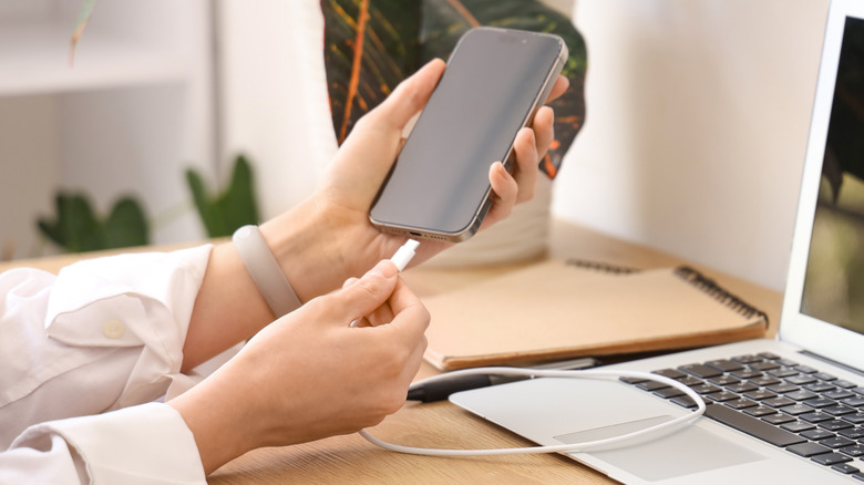 A woman plugging a USB cable into a phone