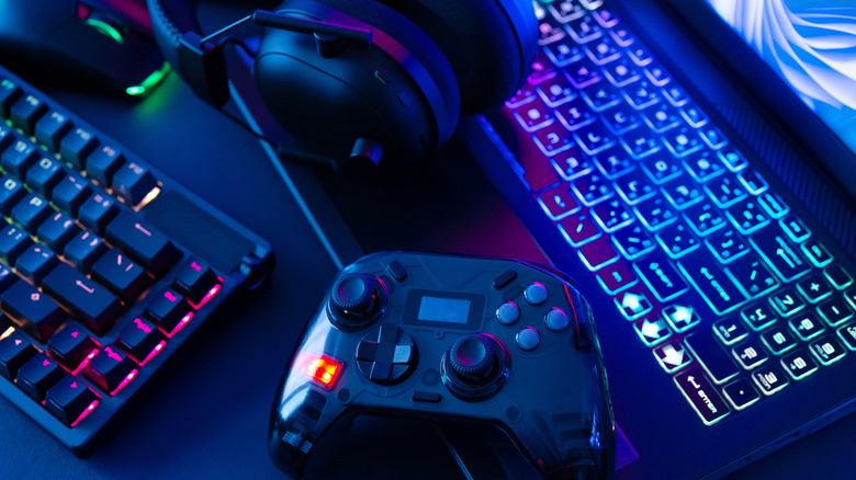 A gamepad, keyboard, headphones, laptop, and mouse lit with RGB