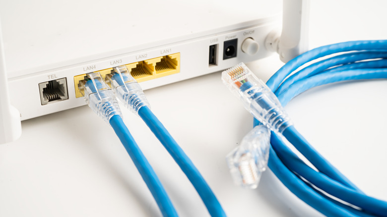 two blue ethernet cables connected to a wireless router with another on the side on a white table