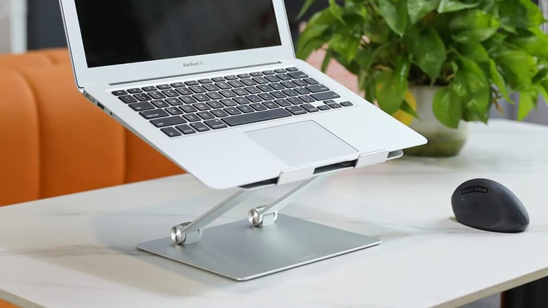 An image of a silver MacBook Air sitting on top of an Amazon Basics Ergonomic Laptop Stand