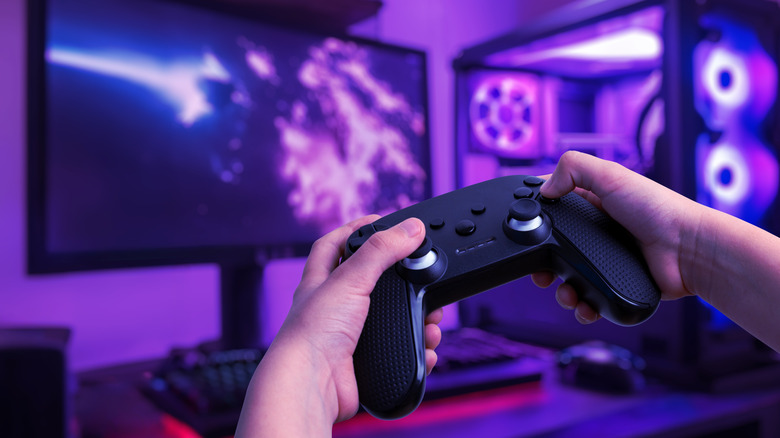 Hands holding a controller to play video games on a PC