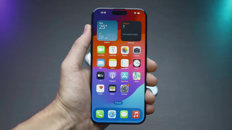 A closeup of a person holding an iPhone displaying its home screen