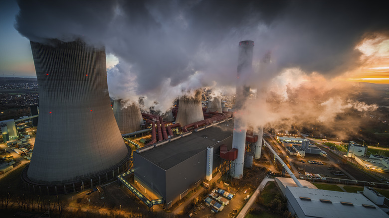 A coal fire powerplant with huge towers and chimneys releasing smoke into the air