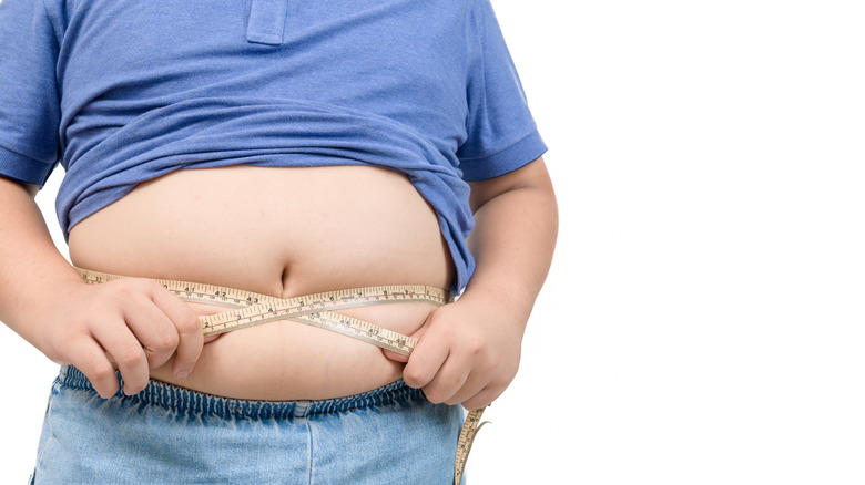 an obese boy measuring his belly
