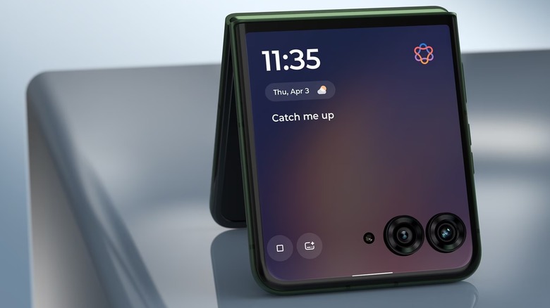 A black Motorola Razr+ sits on a computer rendered table in a tent shape, the image focuses on the device's cover display that is showing the time and the weather