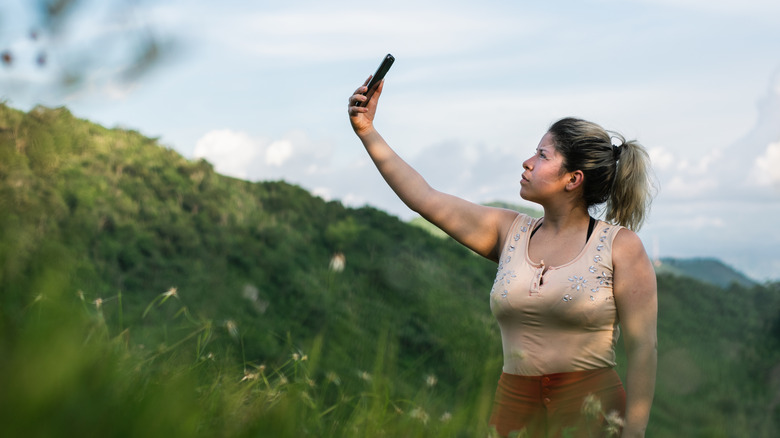woman holding satellite phone up toward the sky