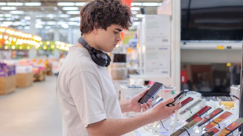 young adult male looking at phones in a store