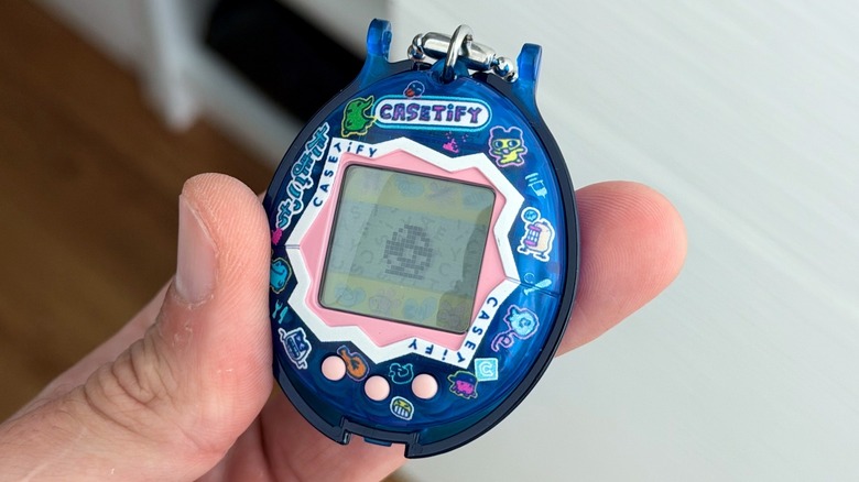 A person holding a Casetify Tamagotchi device