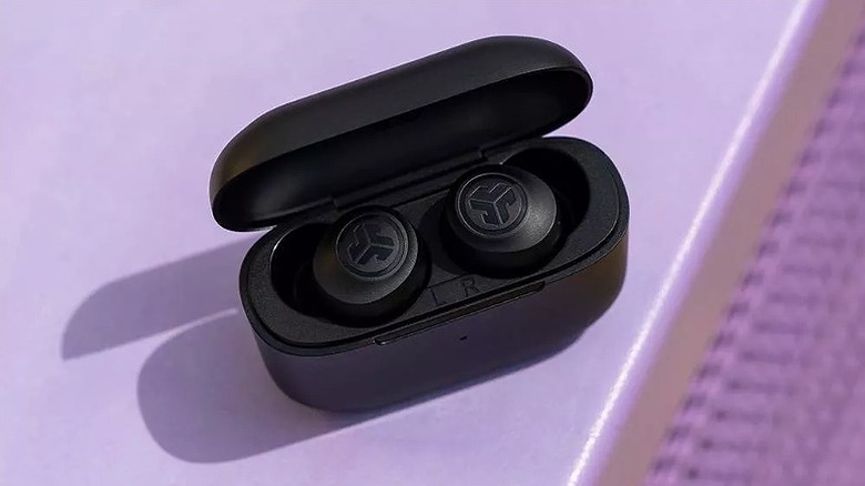 Black earbuds placed on a lilac surface