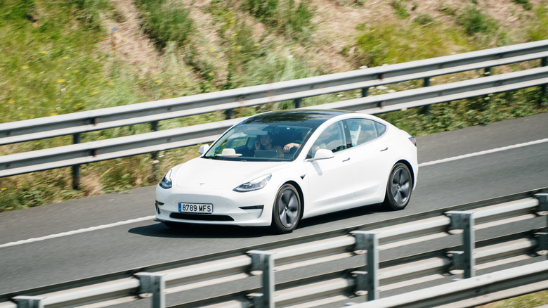 A Tesla Model 3 in motion on a highway