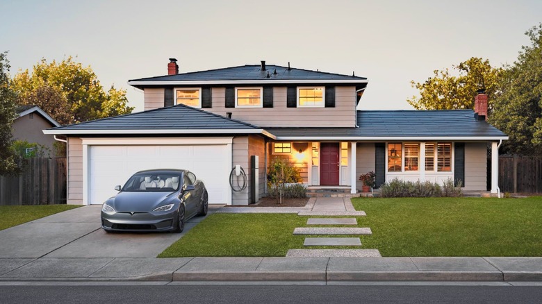 House at sundown with Tesla Solar Roof and car parked outside