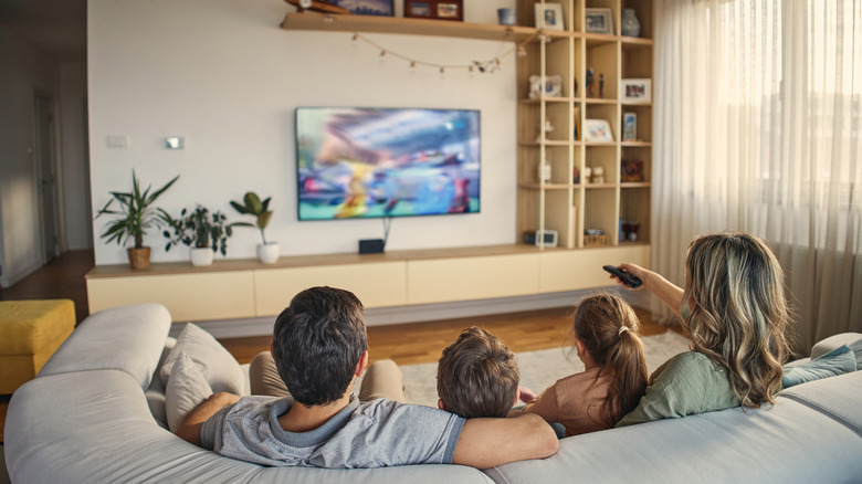 A family on the couch together, watching TV.