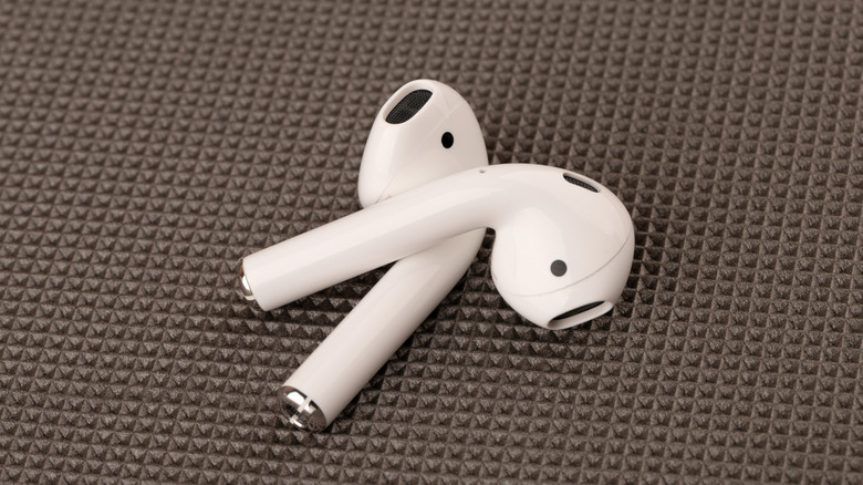 The AirPods 4 placed one on top of the other, both resting on a fabric mat.
