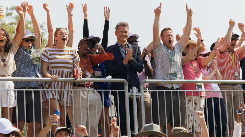 A crowd of sports fans waves their arms in the air