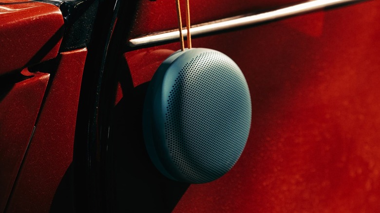 a Bang & Olufsen Beosound A1 (3rd Generation) speaker hanging on a red surface