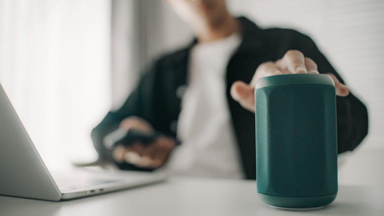 a person reaching for a Bluetooth speaker to connect it to their device