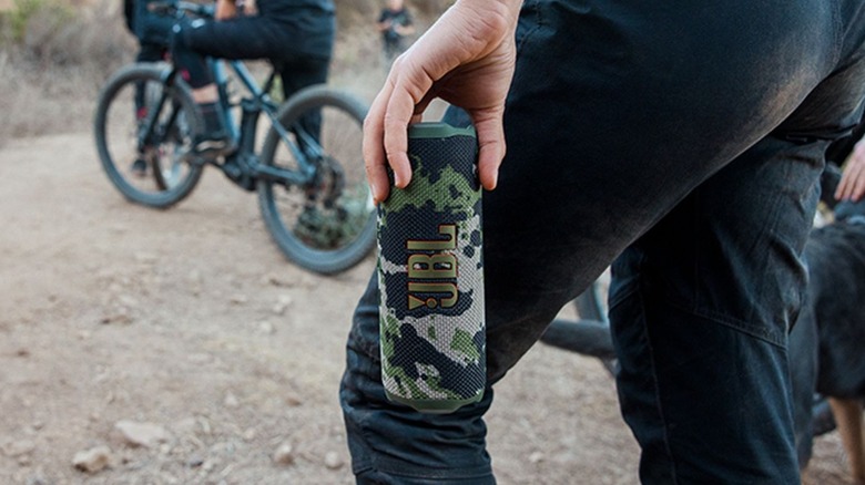 Woman holding camo colored JBL Flip 7 speaker