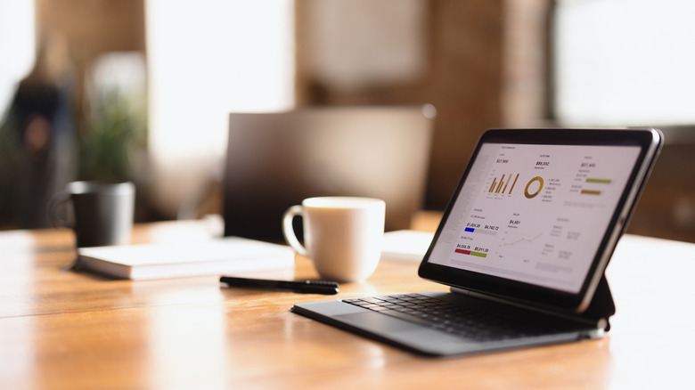 A portable monitor and keyboard on a wooden table next to a coffee cup