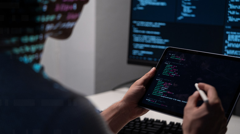 A person coding on a portable monitor with a stylus