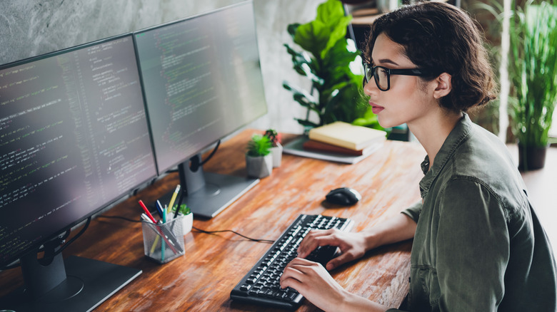 A person developing code on a computer in their home office.