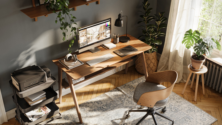 An angled top-down view of a home office with a computer and headphones on a desk, among other gadgets.
