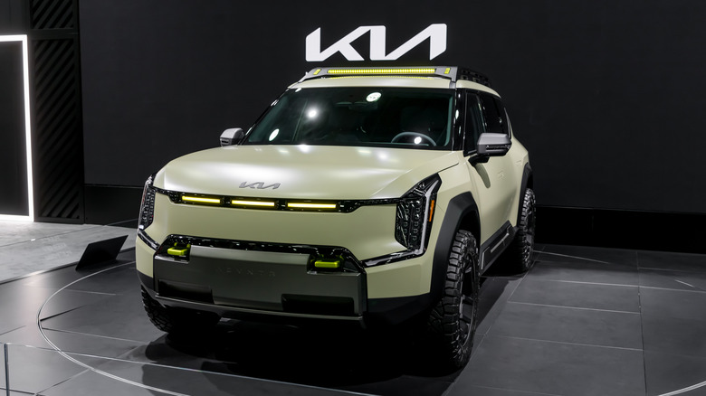 A green Kia EV9 a black backdrop.