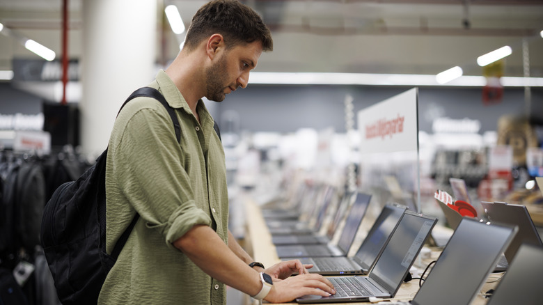 A man testing a laptop in a store.