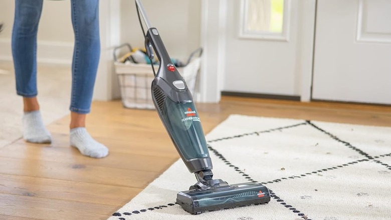 A person using the Bissell Featherweight PowerBrush 2773A corded vacuum to clean a carpet.