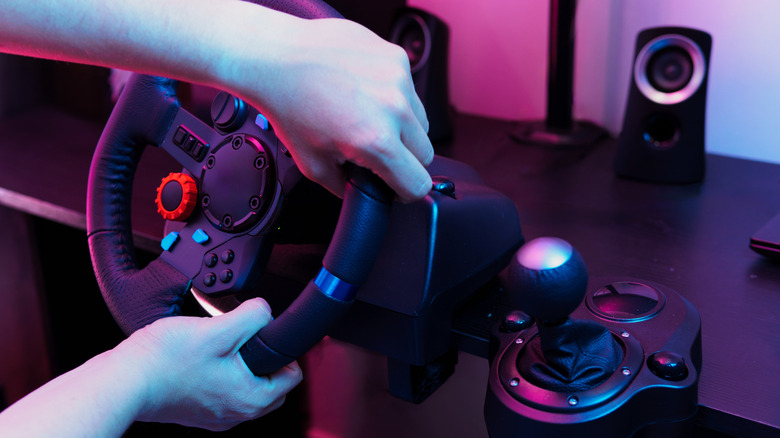 A person using a racing wheel, attached to their desk