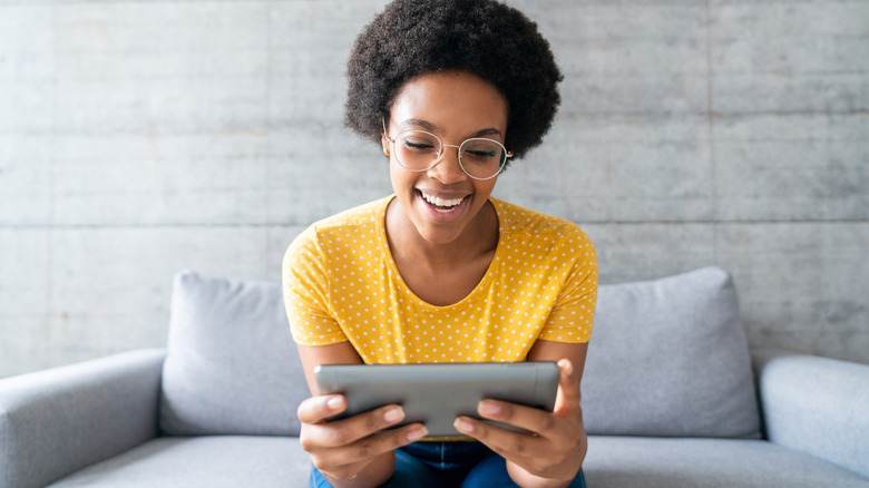 A person holding their iPad in both hands and smiling