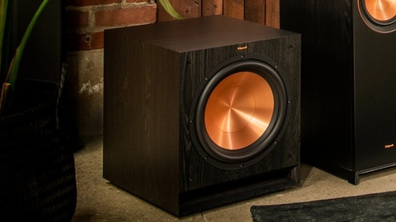 The Klipsch SPL-120 in a rustic room next to a speaker