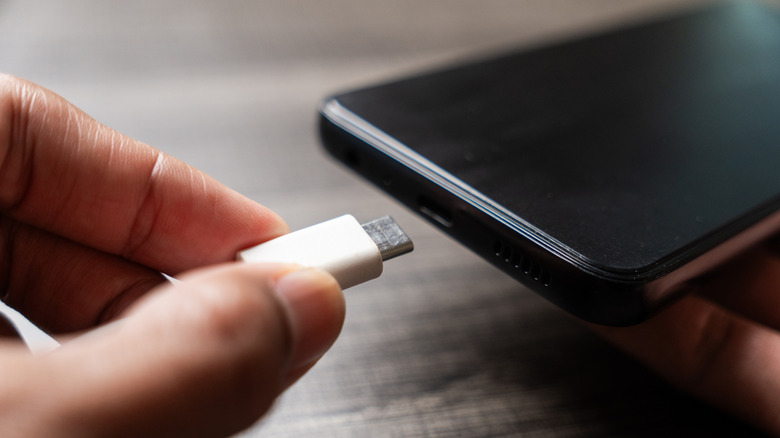 A person inserting a USB-C cable into a smartphone