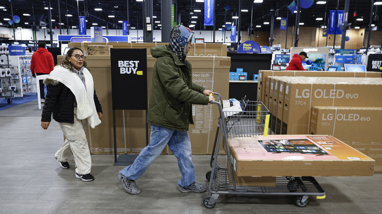 Shoppers at a Best Buy wheeling out a new TV.