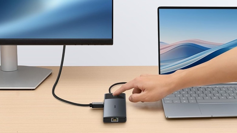 A person touching the screen lock button on the Baseus Metal Gleam Series II 10-in-1 USB Hub