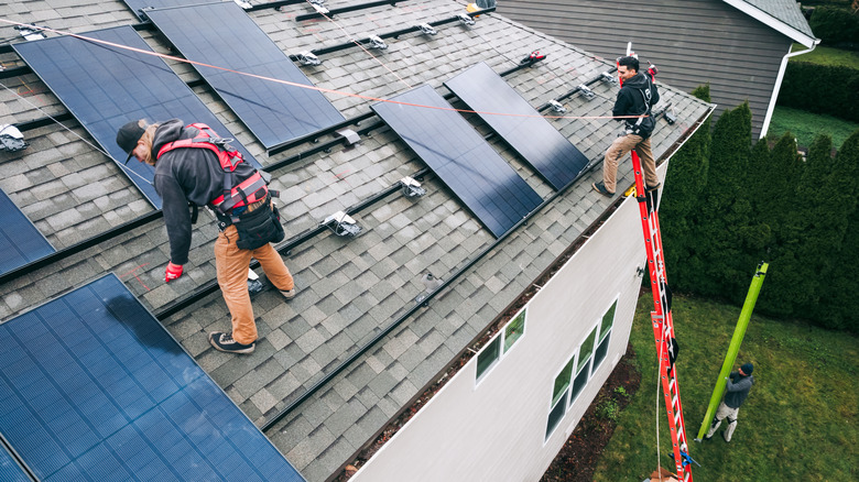 Workers installing solar panels on a residential home's roof.