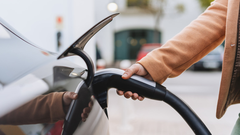 A person plugging in their EV to charge
