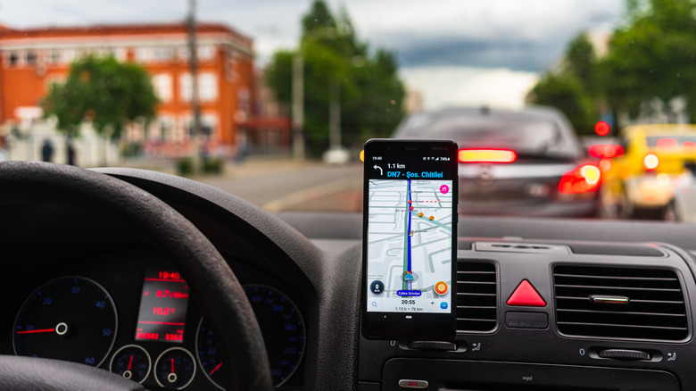 A person using he Waze app running on a phone mounted on a car dashboard